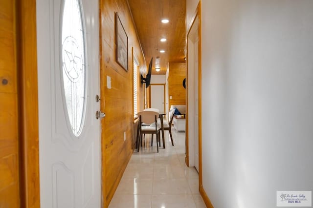 hallway featuring wood walls and light tile patterned flooring