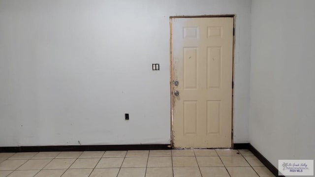 unfurnished room with light tile patterned floors and baseboards