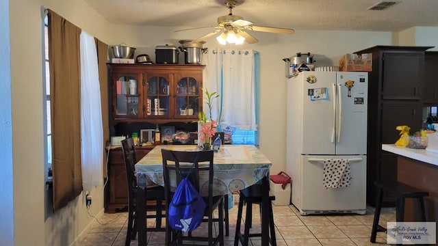 dining area with light tile patterned floors, ceiling fan, visible vents, and a textured ceiling