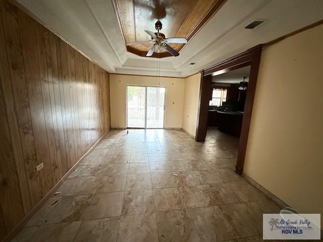 spare room with ceiling fan, a raised ceiling, and a healthy amount of sunlight