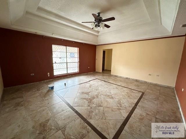 empty room featuring ceiling fan, a raised ceiling, and a textured ceiling