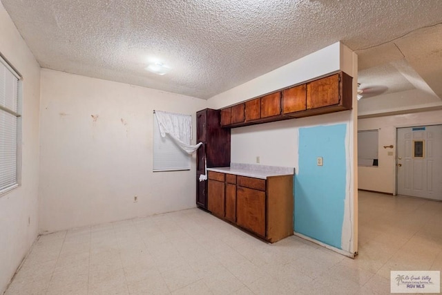 kitchen with ceiling fan, light countertops, light floors, and a textured ceiling