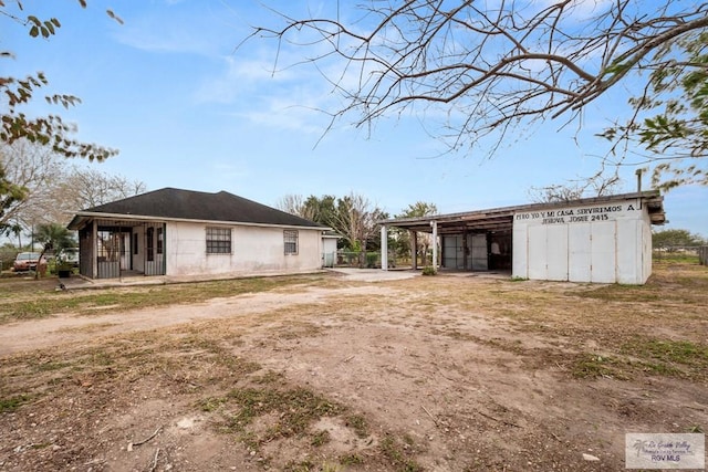 exterior space with driveway, a carport, and an outdoor structure