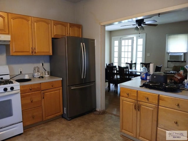 609 E Filmore Ave, Harlingen, TX 78550 - kitchen with freestanding refrigerator, white range with gas stovetop, under cabinet range hood, ceiling fan, and cooling unit