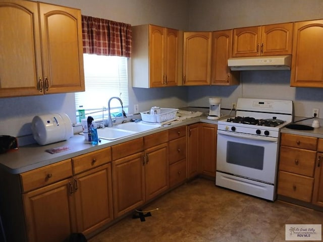 609 E Filmore Ave, Harlingen, TX 78550 - kitchen with under cabinet range hood, white gas range oven, light countertops, and brown cabinets