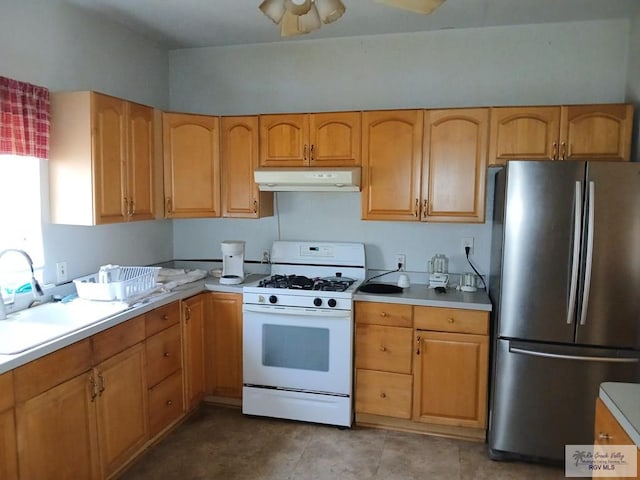 609 E Filmore Ave, Harlingen, TX 78550 - kitchen with freestanding refrigerator, gas range gas stove, under cabinet range hood, and light countertops