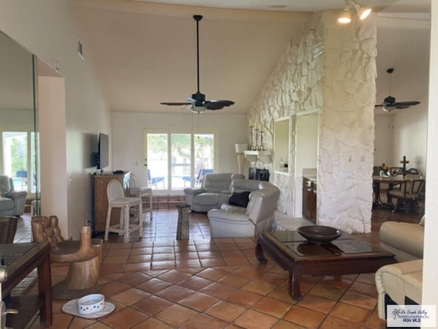 living room featuring tile patterned floors, a stone fireplace, ceiling fan, and high vaulted ceiling