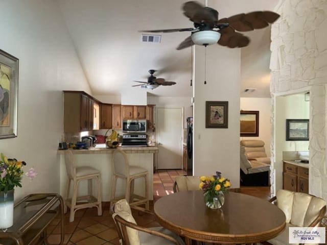 dining room with ceiling fan, light tile patterned flooring, and lofted ceiling