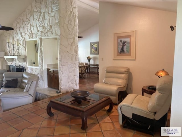 living room featuring tile patterned flooring, vaulted ceiling, and a stone fireplace