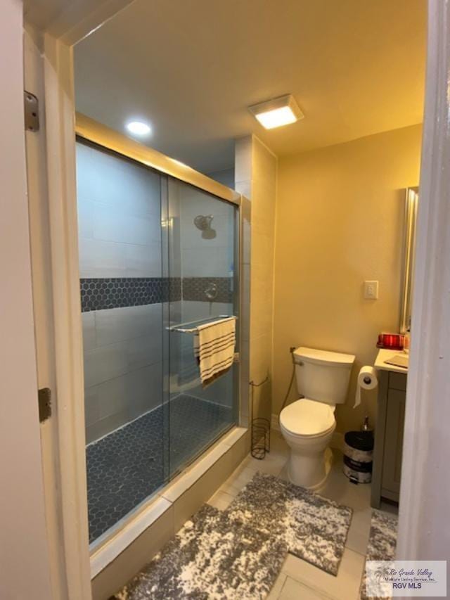 bathroom with tile patterned flooring, vanity, toilet, and a shower with door