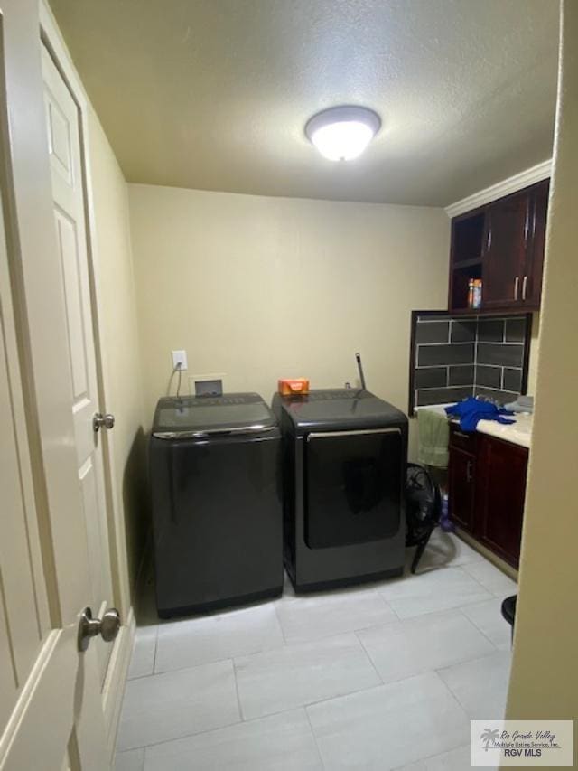 clothes washing area with light tile patterned floors, washing machine and dryer, and a textured ceiling