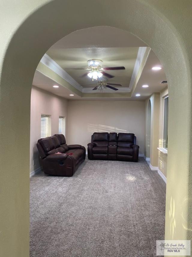 living room with carpet flooring, ceiling fan, and a raised ceiling