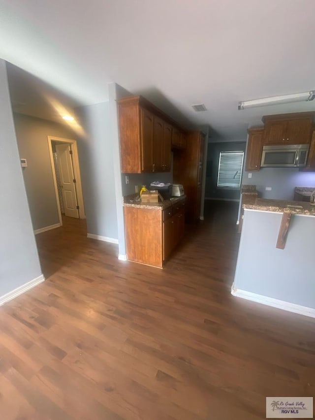 710 5th St Unit 5, Harlingen, TX 78550 - kitchen with stainless steel microwave, dark wood-style floors, and light stone countertops