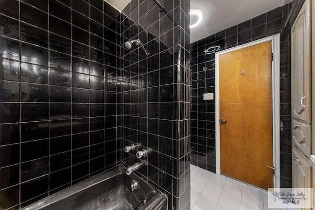 bathroom with tiled shower / bath, tile walls, and tile patterned floors