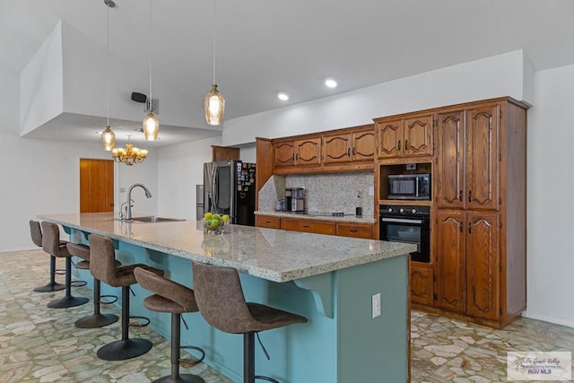 kitchen with black oven, built in microwave, hanging light fixtures, a center island with sink, and fridge with ice dispenser