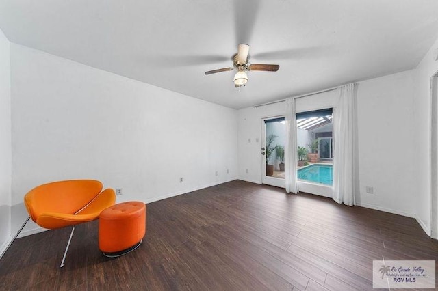 sitting room with dark wood-type flooring and ceiling fan