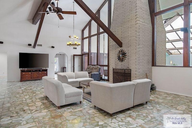 living room with a brick fireplace, ceiling fan with notable chandelier, high vaulted ceiling, and beamed ceiling