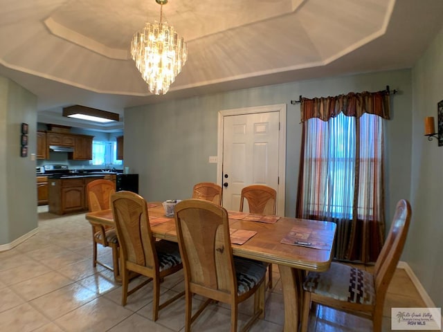 dining area featuring a notable chandelier, light tile patterned flooring, and a tray ceiling