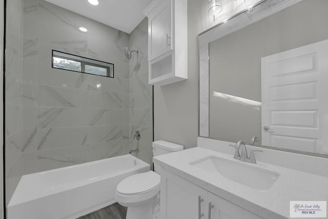 full bathroom featuring tiled shower / bath combo, toilet, and vanity