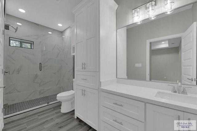 bathroom featuring a shower with shower door, toilet, wood-type flooring, and vanity