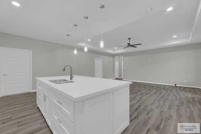 kitchen with ceiling fan, a kitchen island with sink, sink, pendant lighting, and white cabinets