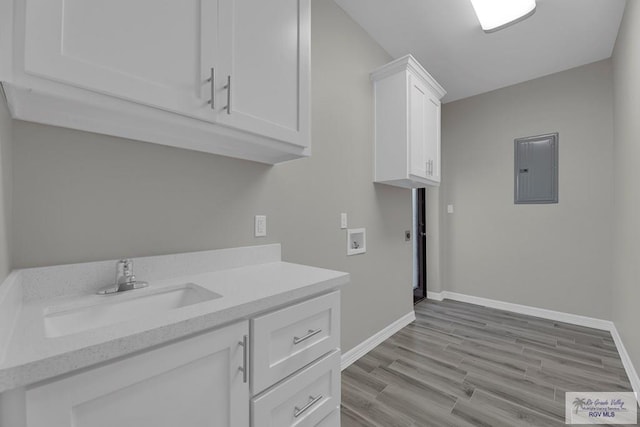 clothes washing area featuring sink, cabinets, washer hookup, electric panel, and light hardwood / wood-style floors