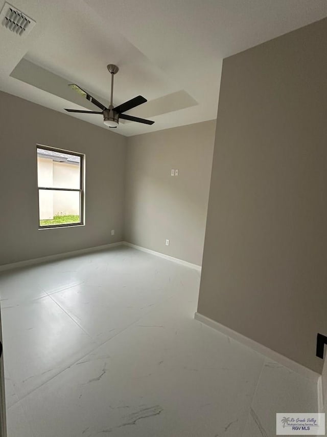 empty room featuring baseboards, visible vents, ceiling fan, and a raised ceiling