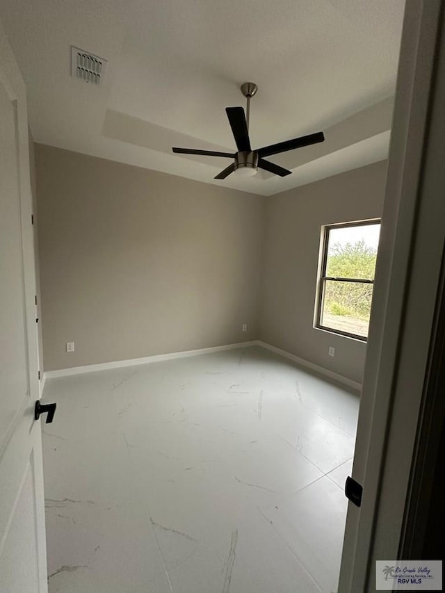 unfurnished room with ceiling fan, visible vents, and baseboards