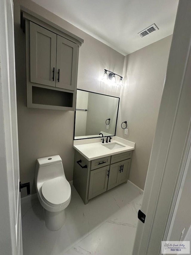 bathroom with toilet, vanity, visible vents, baseboards, and marble finish floor