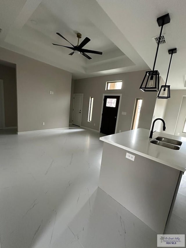 kitchen featuring a raised ceiling, a sink, marble finish floor, and ceiling fan