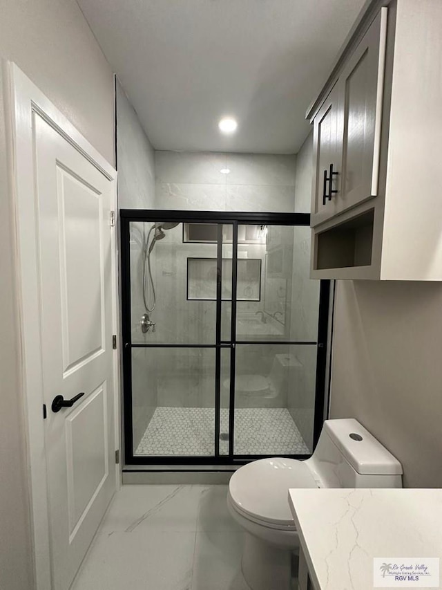 full bathroom featuring marble finish floor, a shower stall, toilet, and vanity