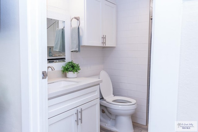 bathroom with vanity, toilet, and tile walls