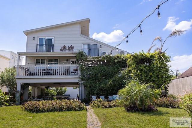 rear view of property featuring a balcony and a yard