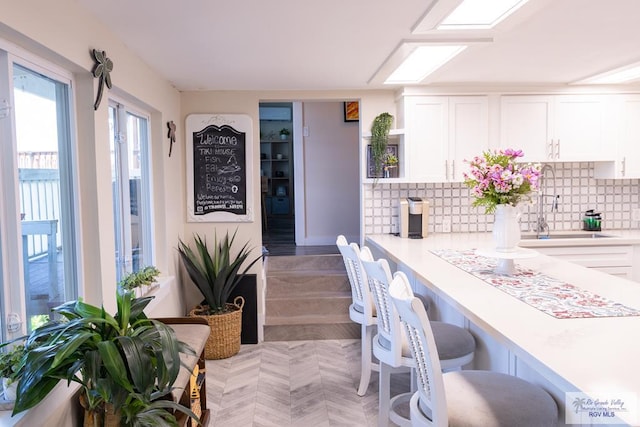 kitchen with backsplash, sink, and white cabinets