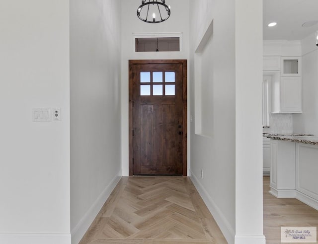 doorway featuring baseboards, recessed lighting, and an inviting chandelier