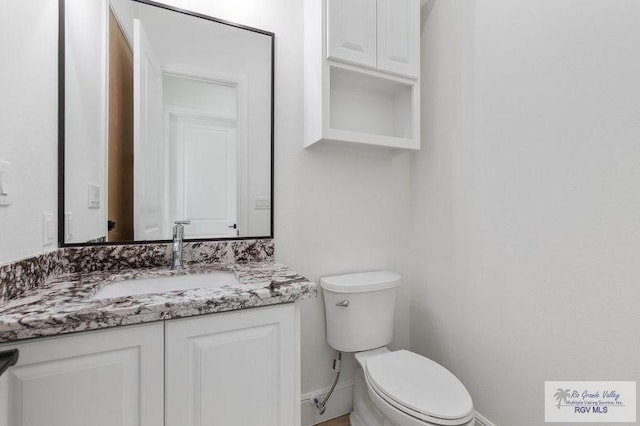 bathroom featuring vanity, toilet, and baseboards