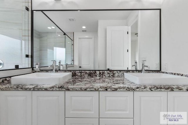 full bathroom with recessed lighting, double vanity, a sink, and a shower stall