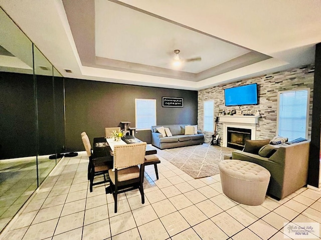 tiled living room featuring a raised ceiling and ceiling fan