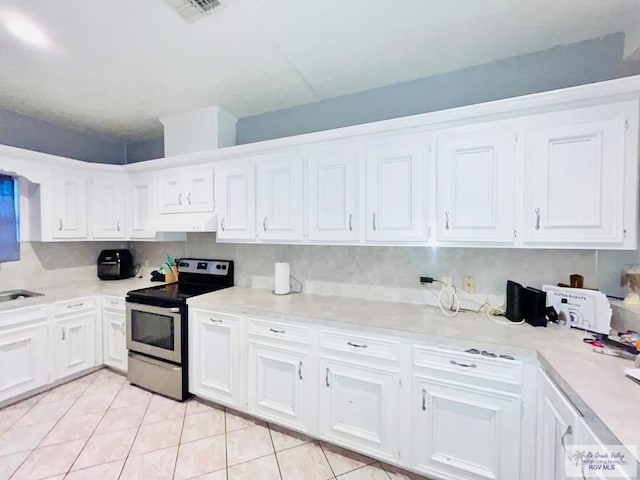 kitchen with white cabinets, stainless steel electric range, light tile patterned flooring, and tasteful backsplash