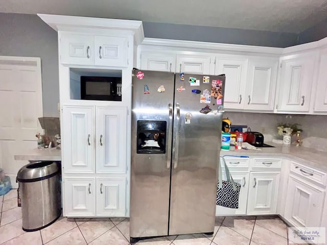 kitchen featuring stainless steel fridge, white cabinetry, and light tile patterned flooring