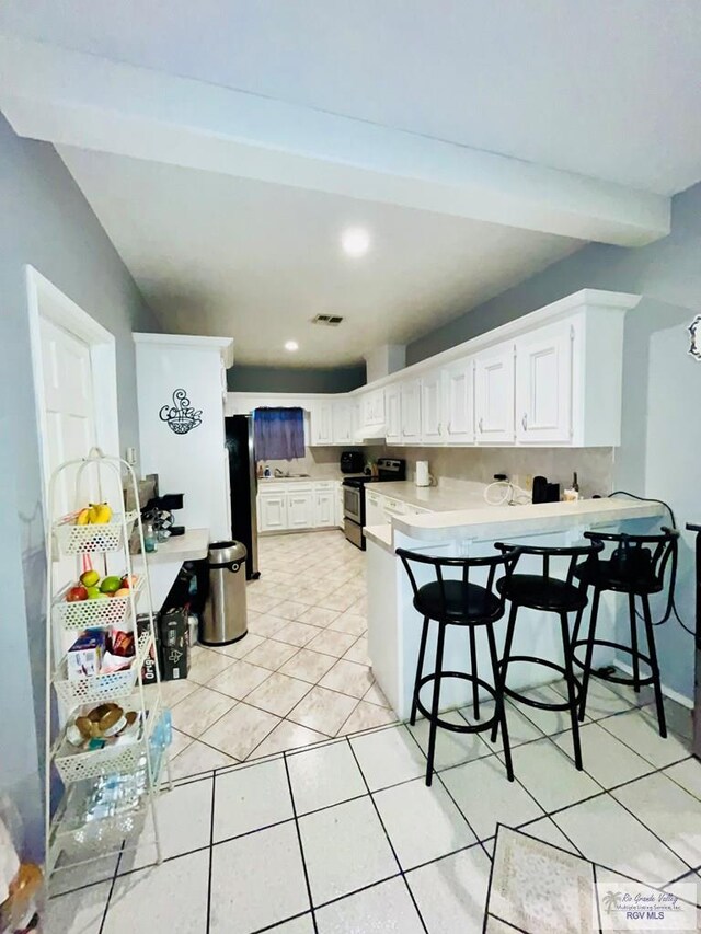 kitchen with a breakfast bar, white cabinets, light tile patterned floors, appliances with stainless steel finishes, and kitchen peninsula