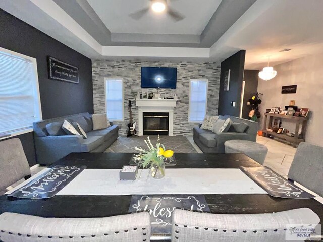 living room with a raised ceiling and ceiling fan