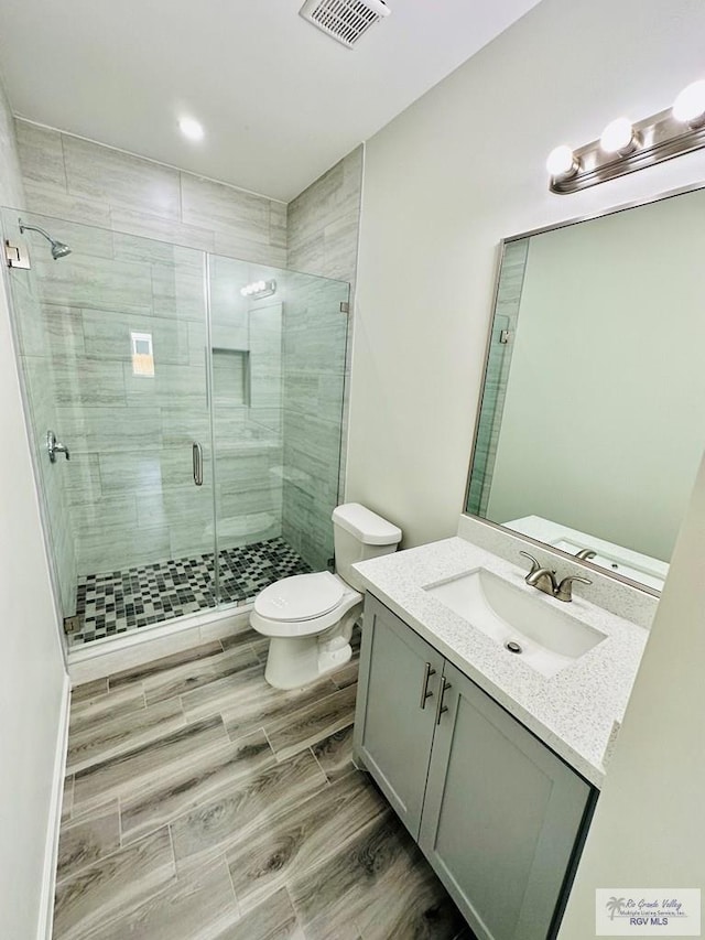 bathroom featuring vanity, toilet, and a shower with door