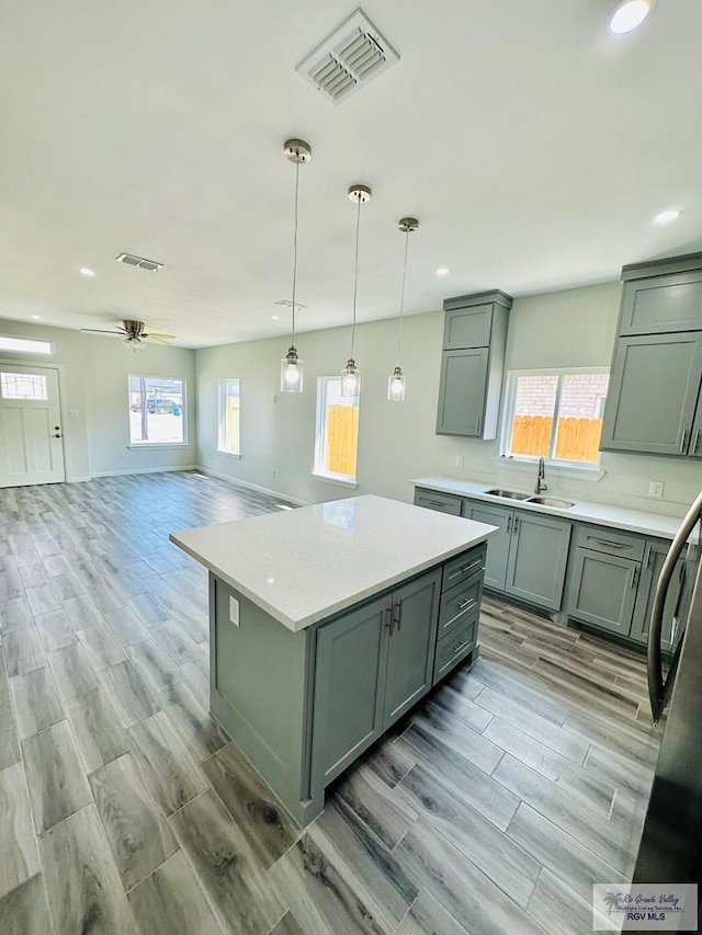 kitchen with ceiling fan, sink, a healthy amount of sunlight, and light wood-type flooring