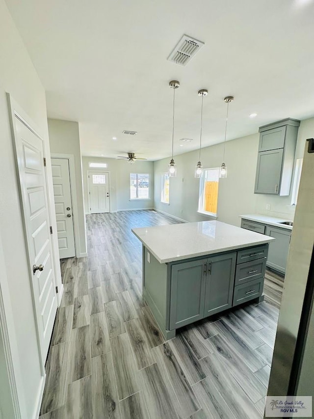 kitchen with ceiling fan, a kitchen island, pendant lighting, and light wood-type flooring