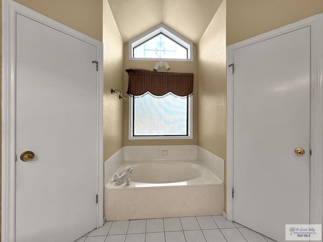 bathroom with tile patterned floors, lofted ceiling, and a tub