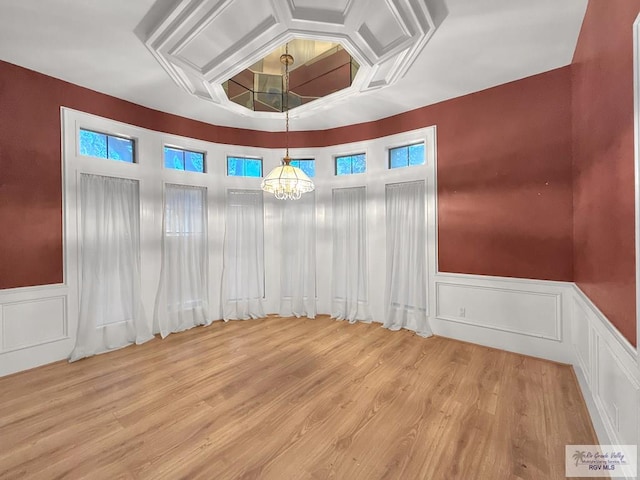 spare room with a chandelier and light wood-type flooring