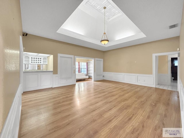 unfurnished living room with light hardwood / wood-style floors and a raised ceiling