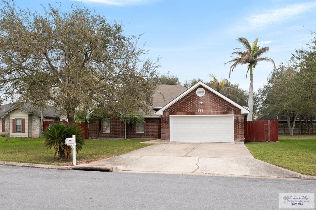 714 Easy St, San Benito, TX 78586 - single story home with a garage, brick siding, fence, driveway, and a front lawn