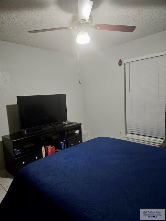 tiled bedroom with a textured ceiling and ceiling fan